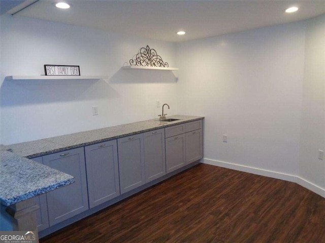 kitchen with sink, light stone counters, dark hardwood / wood-style flooring, and gray cabinets