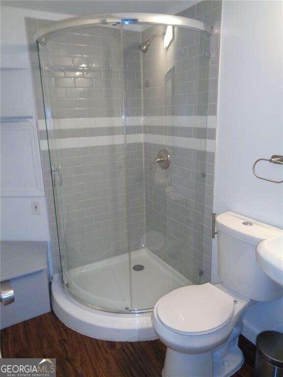 bathroom featuring toilet, hardwood / wood-style floors, and walk in shower