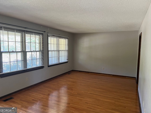 empty room featuring a textured ceiling and hardwood / wood-style floors