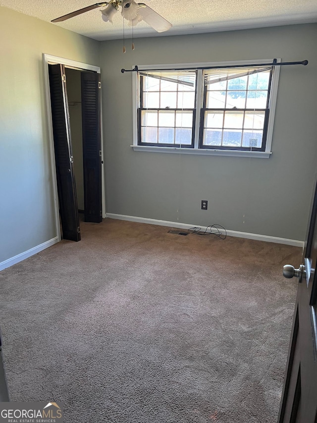 carpeted empty room featuring ceiling fan and a textured ceiling