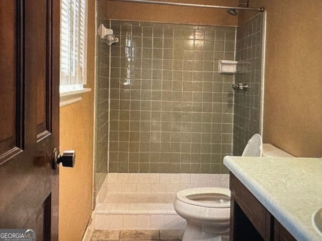 bathroom with vanity, tiled shower, and toilet