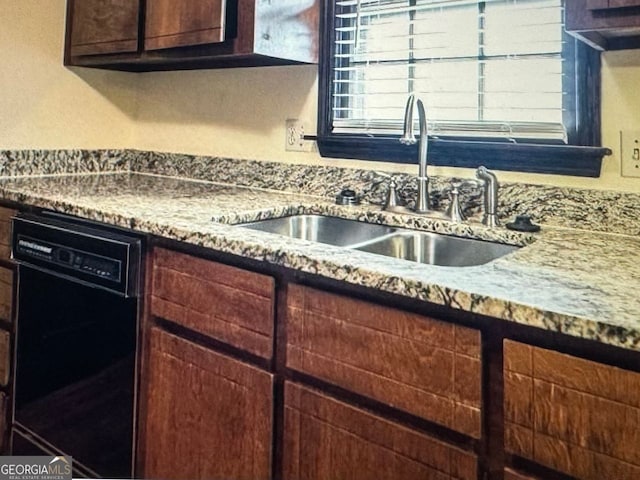 kitchen featuring dark brown cabinetry, black dishwasher, sink, and light stone countertops