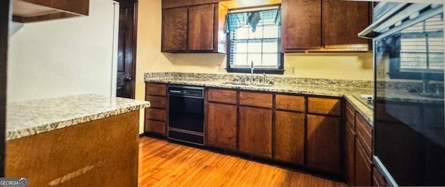 kitchen featuring light hardwood / wood-style flooring, black dishwasher, light stone countertops, and sink