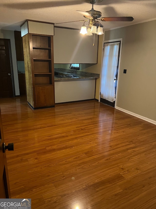 kitchen with crown molding, a textured ceiling, dark wood-type flooring, and ceiling fan