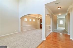 hallway with ornamental molding, hardwood / wood-style flooring, and a chandelier