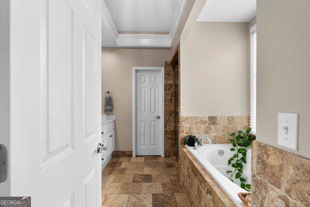 bathroom featuring vanity, a relaxing tiled tub, and ornamental molding