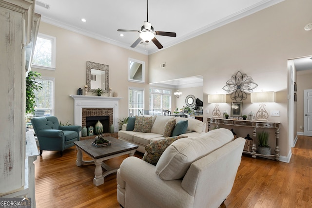 living room with wood-type flooring, a towering ceiling, a wealth of natural light, and ornamental molding