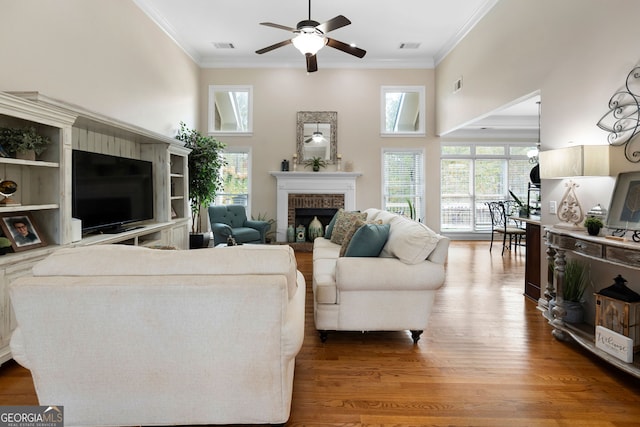 living room with a fireplace, hardwood / wood-style floors, ceiling fan, and ornamental molding