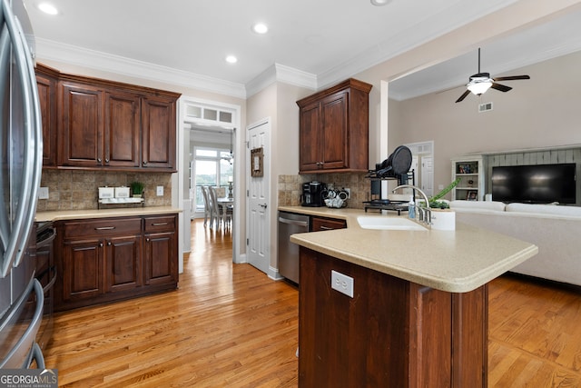 kitchen with appliances with stainless steel finishes, ceiling fan, crown molding, sink, and light hardwood / wood-style floors