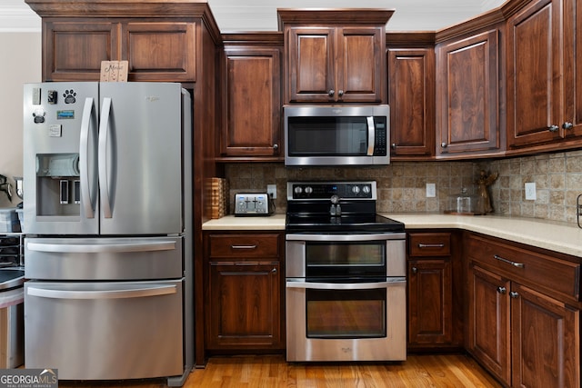 kitchen with light wood-type flooring, backsplash, dark brown cabinets, stainless steel appliances, and crown molding