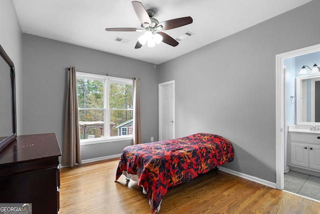 bedroom featuring light hardwood / wood-style floors, ensuite bath, ceiling fan, and sink