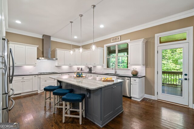 kitchen with appliances with stainless steel finishes, wall chimney exhaust hood, and white cabinets