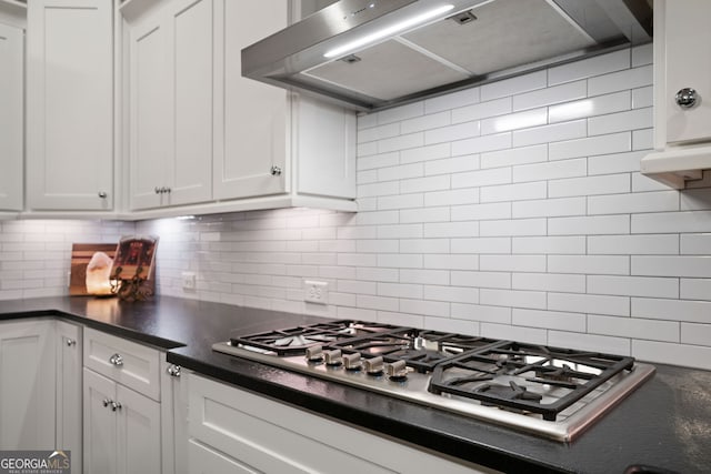 kitchen featuring decorative backsplash, ventilation hood, white cabinets, and stainless steel gas stovetop