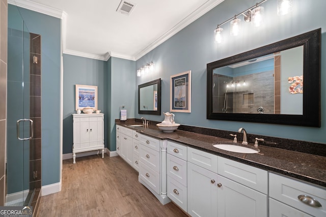 bathroom featuring vanity, ornamental molding, wood-type flooring, and a shower with door