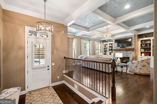 foyer with hardwood / wood-style floors, a chandelier, beamed ceiling, and a fireplace