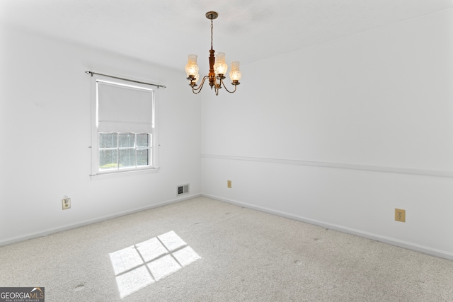 carpeted empty room with a chandelier