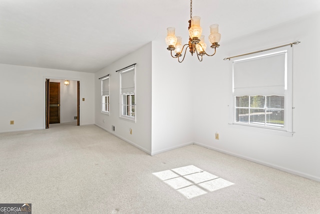 spare room featuring a notable chandelier and light colored carpet