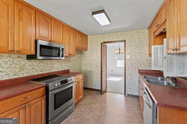 kitchen featuring a notable chandelier, a textured ceiling, appliances with stainless steel finishes, and sink