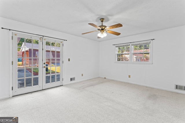 spare room with french doors, light carpet, and ceiling fan