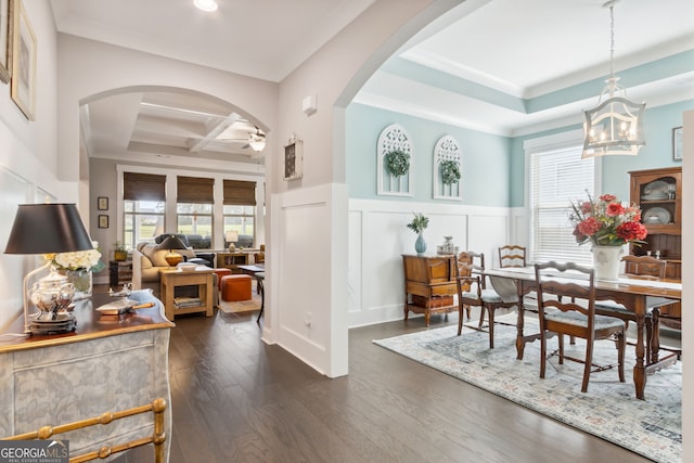 dining space featuring ceiling fan with notable chandelier, coffered ceiling, beamed ceiling, dark wood-type flooring, and crown molding