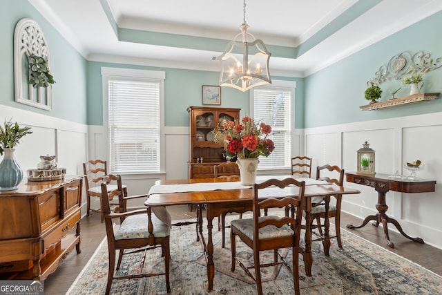 dining area featuring a notable chandelier, dark wood-type flooring, and a raised ceiling