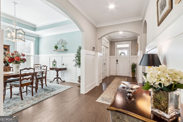 foyer with dark wood-type flooring and crown molding