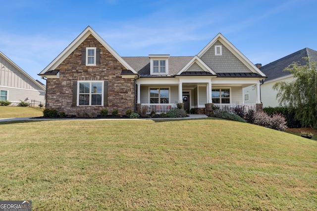 craftsman-style house featuring stone siding, a standing seam roof, covered porch, and a front yard