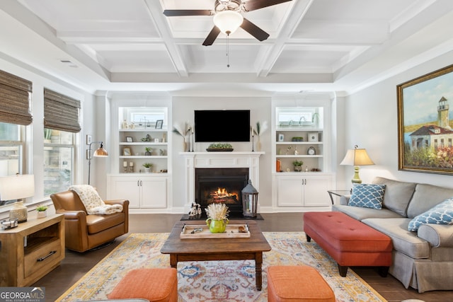 living room with ceiling fan, coffered ceiling, beamed ceiling, dark wood-type flooring, and built in shelves