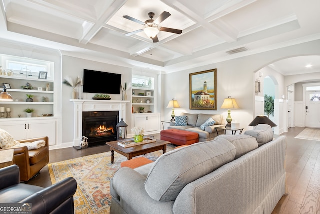 living area featuring hardwood / wood-style floors, ceiling fan, arched walkways, coffered ceiling, and visible vents