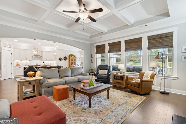 living room with ceiling fan, beamed ceiling, dark wood-type flooring, crown molding, and coffered ceiling