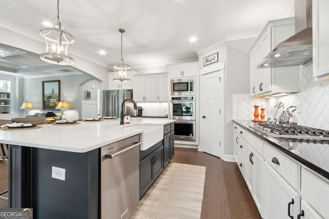 kitchen with wall chimney range hood, a large island, hanging light fixtures, backsplash, and wood-type flooring