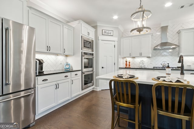 kitchen with decorative backsplash, dark hardwood / wood-style flooring, appliances with stainless steel finishes, white cabinetry, and wall chimney exhaust hood