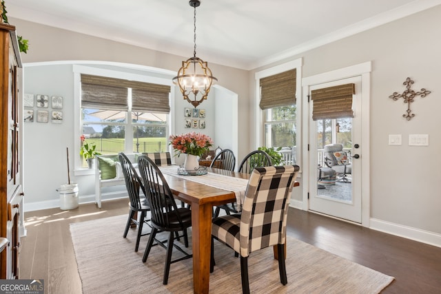 dining space with crown molding, dark hardwood / wood-style flooring, and an inviting chandelier