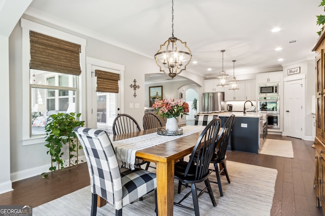 dining room featuring ornamental molding, sink, an inviting chandelier, and dark hardwood / wood-style flooring