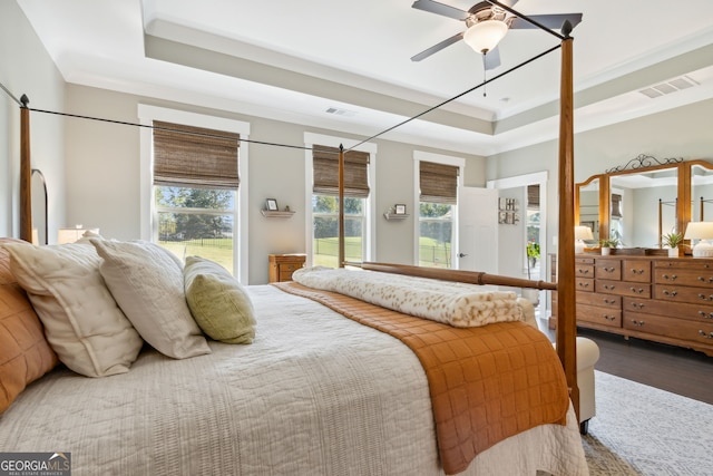 bedroom with hardwood / wood-style floors, ceiling fan, and a raised ceiling