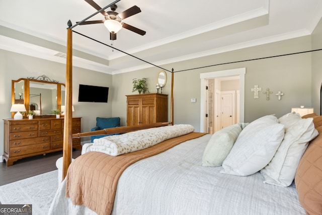 bedroom with a raised ceiling, wood finished floors, visible vents, and crown molding