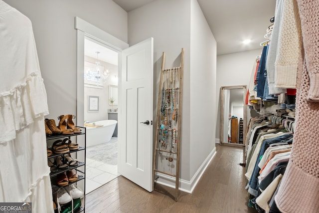 walk in closet with wood finished floors and a notable chandelier