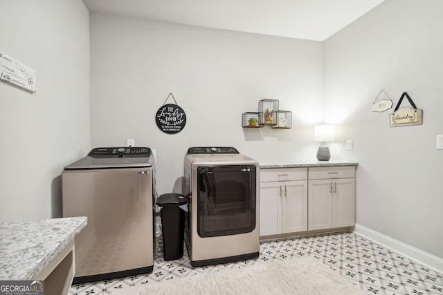 laundry area with washing machine and dryer, baseboards, light floors, and cabinet space