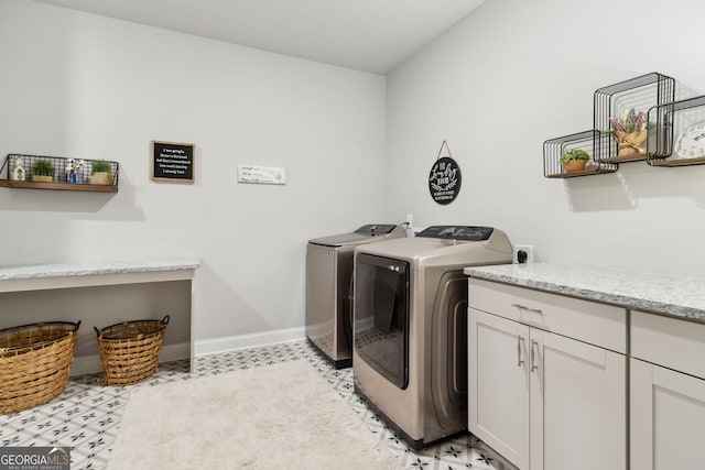 laundry area with separate washer and dryer, baseboards, and cabinet space