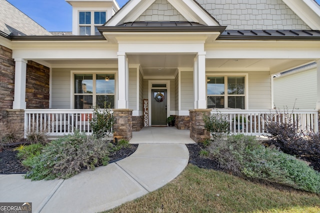 view of exterior entry with metal roof, a standing seam roof, and covered porch