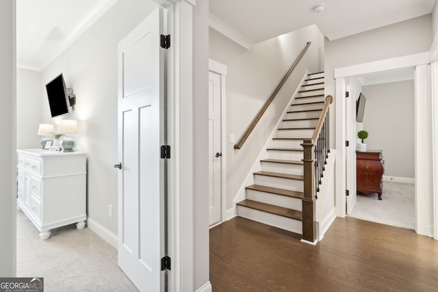 stairs with baseboards, wood finished floors, and ornamental molding