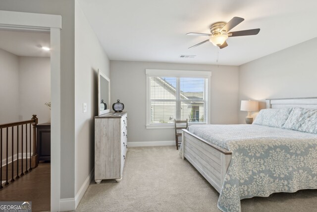 bedroom featuring visible vents, a ceiling fan, baseboards, and light colored carpet