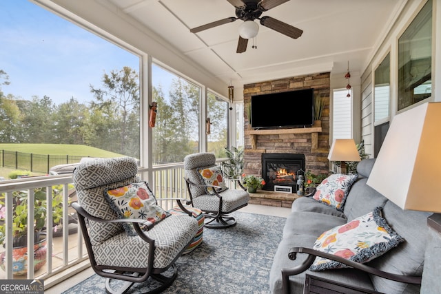 sunroom with a stone fireplace and ceiling fan