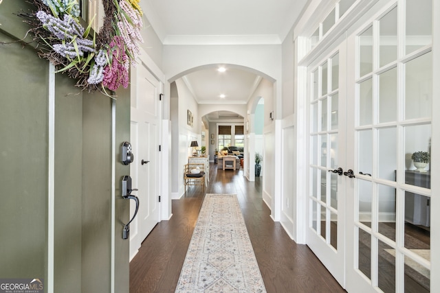 corridor with dark wood-type flooring, ornamental molding, and french doors