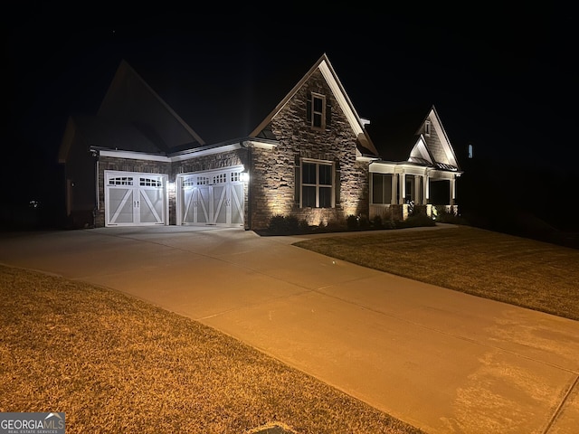 craftsman-style home featuring a garage, driveway, and stone siding
