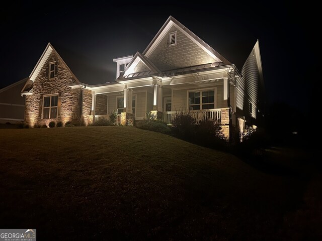craftsman-style home featuring stone siding, a standing seam roof, and covered porch