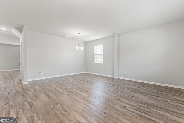 empty room featuring an inviting chandelier and light hardwood / wood-style flooring