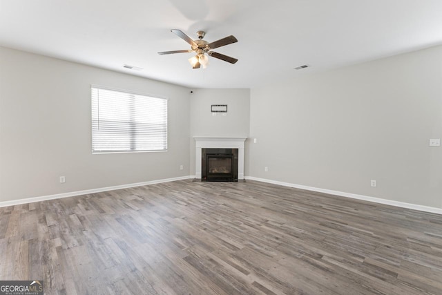 unfurnished living room featuring wood-type flooring, a tile fireplace, and ceiling fan