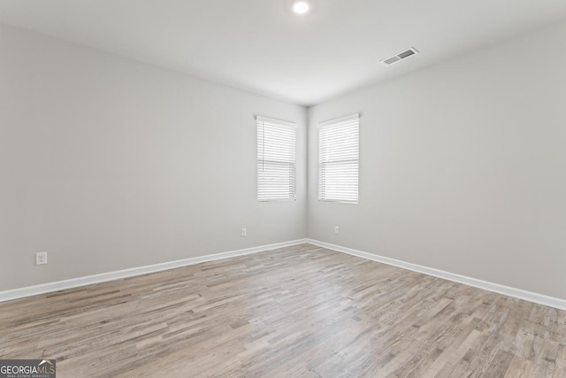 unfurnished room with light wood finished floors, baseboards, and visible vents