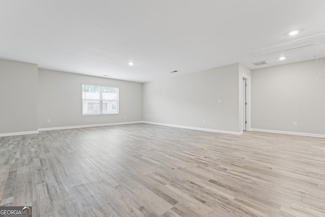 interior space with baseboards, attic access, and light wood-style floors